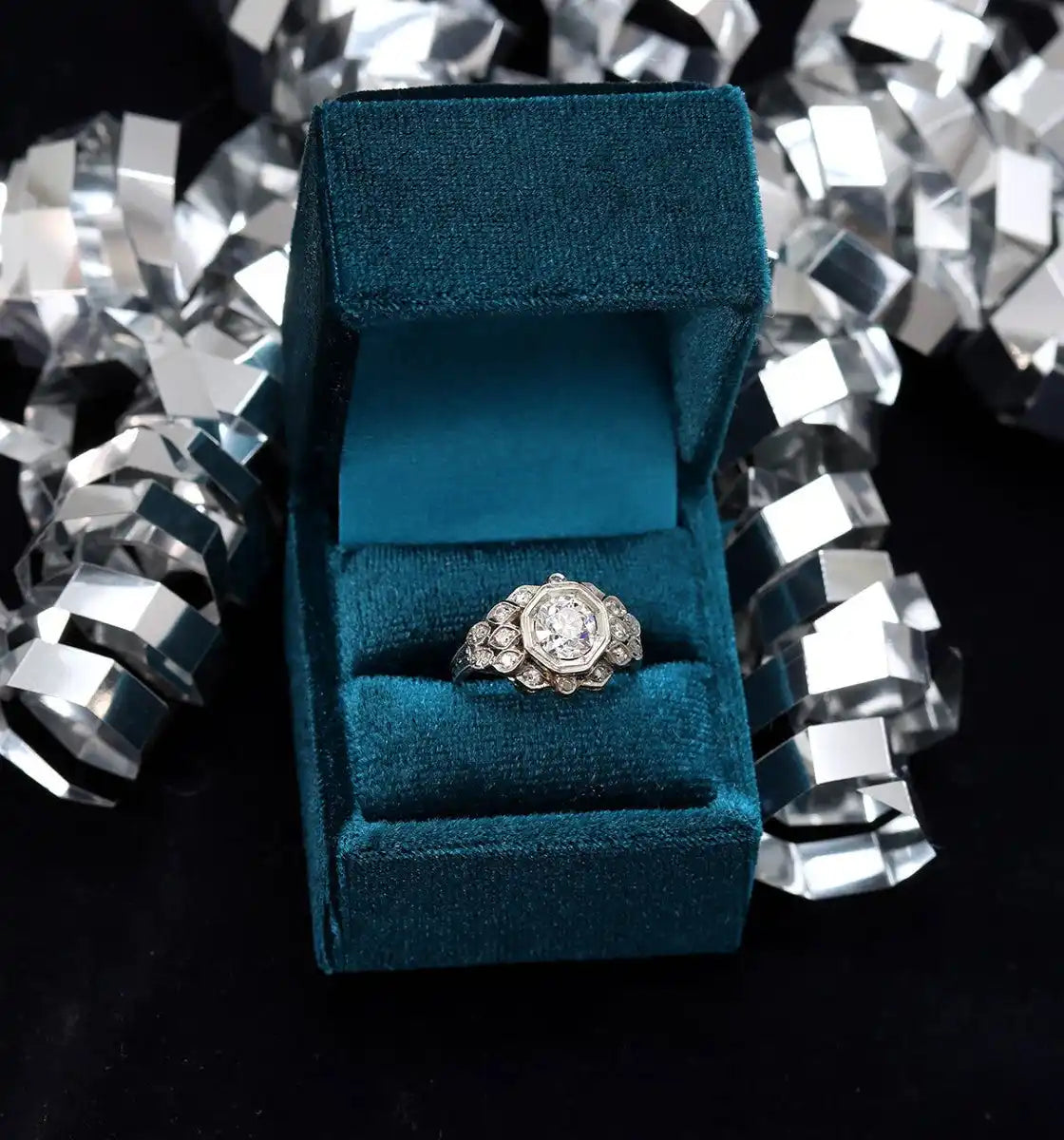 Diamond engagement ring in a teal velvet box.