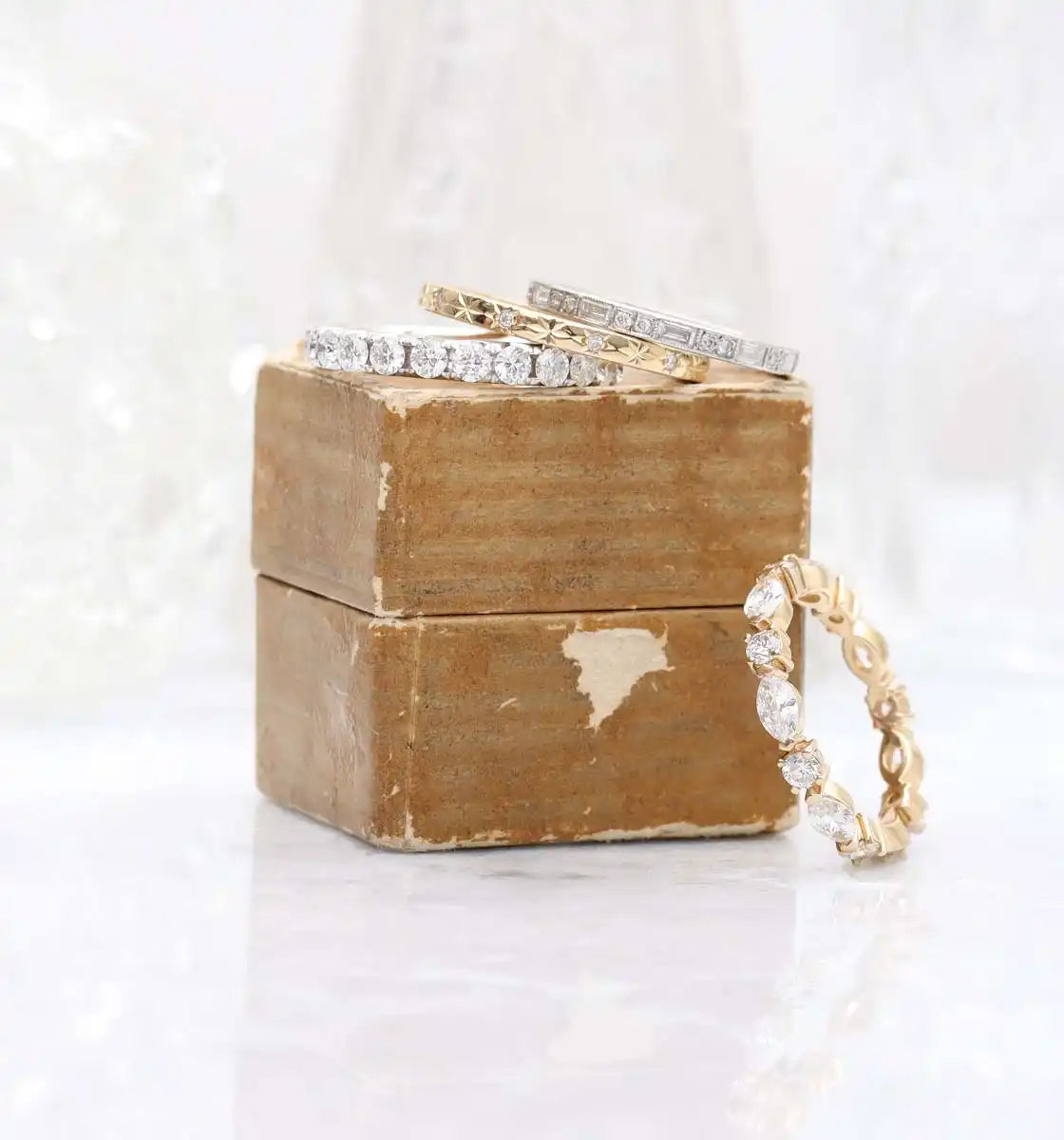 Diamond rings stacked on a weathered brown wooden box.