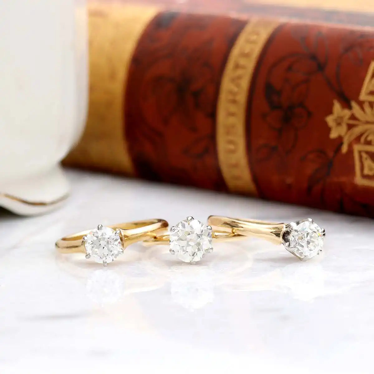 Three gold solitaire diamond engagement rings arranged side by side.